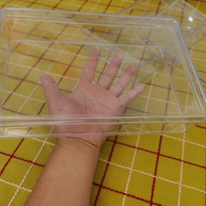 May include: A clear plastic storage box with a lid. The box is empty and is sitting on a yellow and red checkered surface.