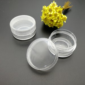 Puede incluir: Tres recipientes de plástico transparente con tapas. Los recipientes son redondos y tienen un acabado liso y brillante. Son perfectos para guardar objetos pequeños como joyas, cosméticos o artículos de artesanía.