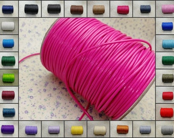 Puede incluir: Un carrete de cordón encerado de color rosa brillante, con una variedad de otros colores de cordón en el fondo.