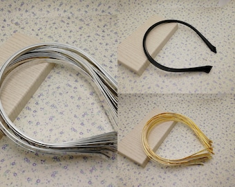 Può includere: Una collezione di cerchietti per capelli argentati, neri e dorati. I cerchietti sono realizzati in un materiale sottile e flessibile e sono progettati per essere indossati sulla testa. I cerchietti sono esposti su una superficie chiara su uno sfondo floreale.