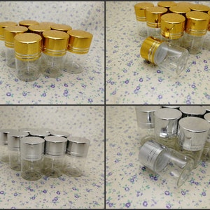 May include: A group of small, clear glass bottles with gold and silver lids. The bottles are arranged in a grid pattern on a white background with a floral pattern.