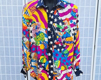 May include: A long-sleeved button-down shirt with a vibrant, colorful pattern. The shirt features a collage of circus clowns, stars, and stripes in shades of yellow, pink, blue, and black. The collar and cuffs are navy blue.