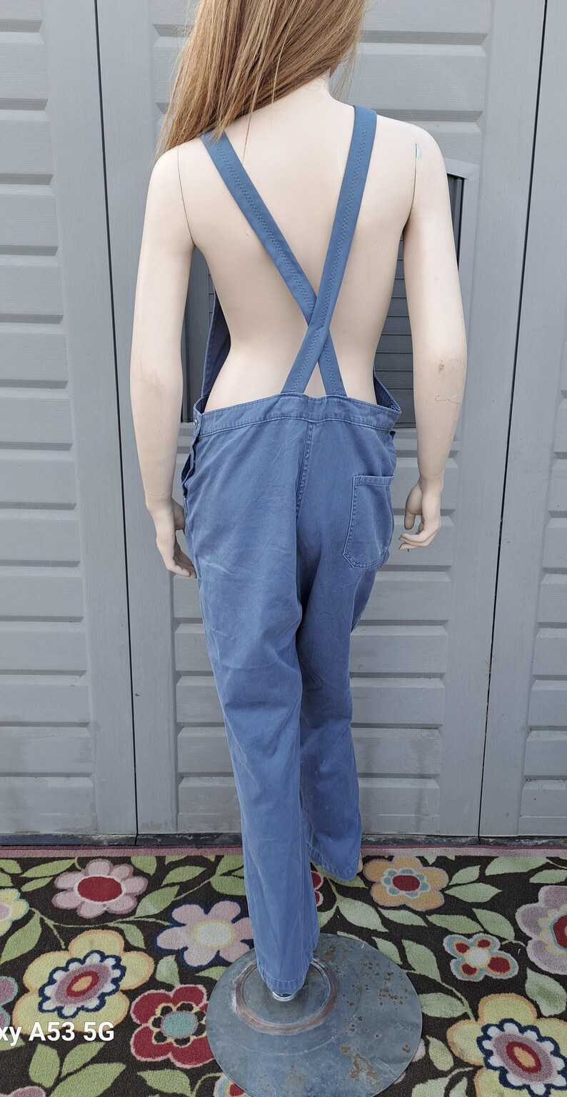 Op de afbeelding: Blauwe denim overall met een gekruist rugband ontwerp. De overall heeft een ontspannen pasvorm en is gemaakt van een zachte, comfortabele stof.