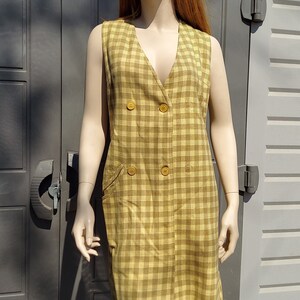 May include: A sleeveless yellow and brown plaid dress with a double-breasted button closure and two pockets.