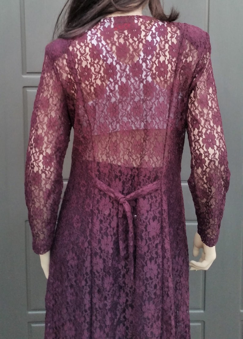 Puede incluir: Un vestido largo de encaje color burdeos con un lazo en la espalda.