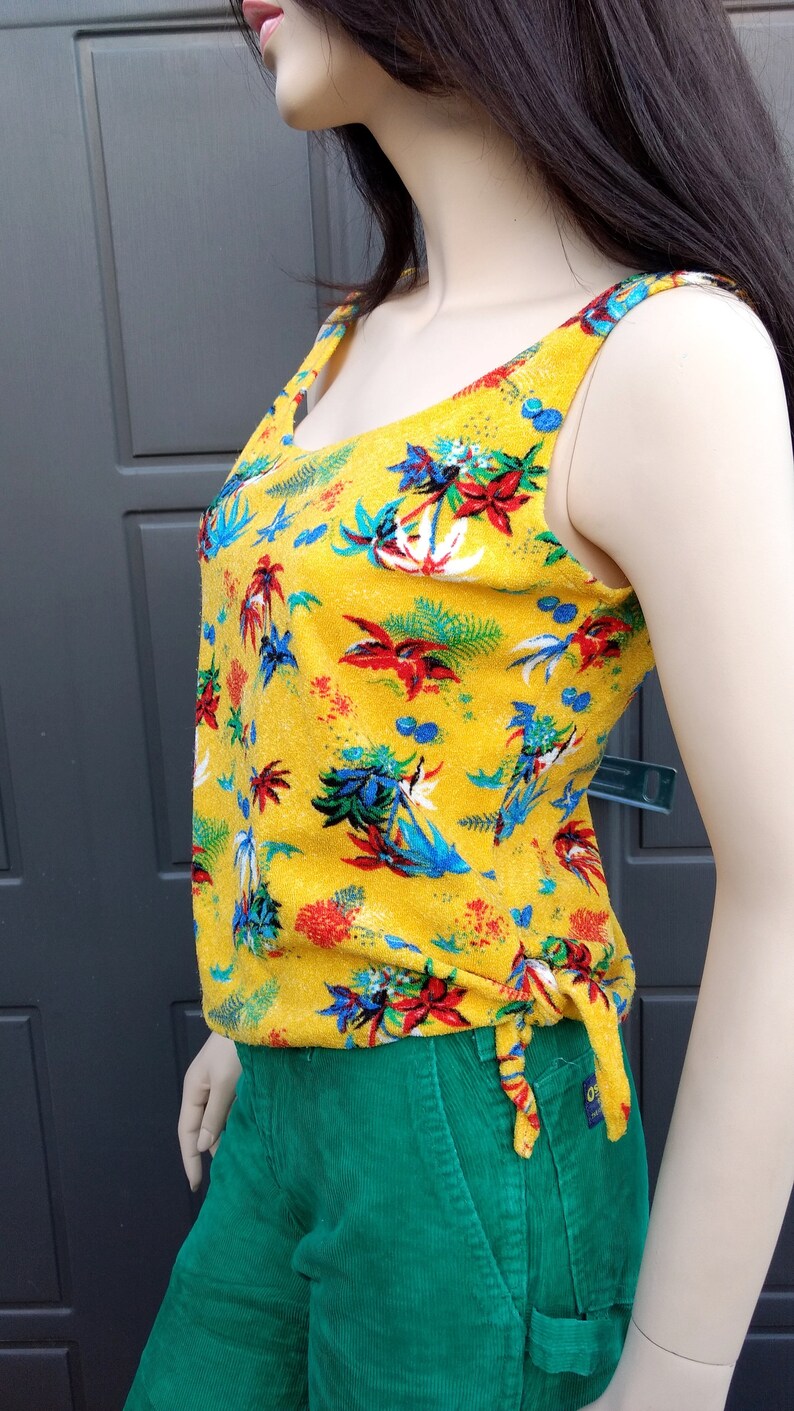 May include: A yellow sleeveless top with a tropical print and a green corduroy skirt.