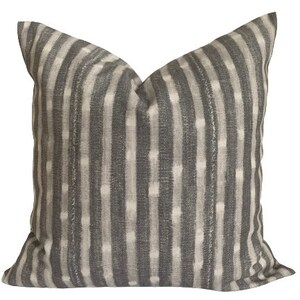May include: A gray and white striped throw pillow with a subtle ikat pattern. The pillow is made of a soft, textured fabric.