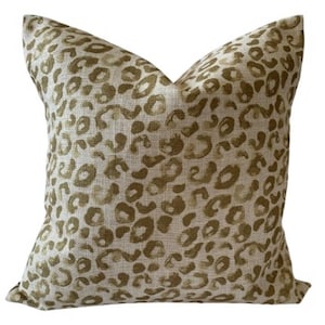 May include: A beige throw pillow with a gold leopard print pattern.