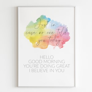 Może przedstawiać: Druk akwarelowy z tłem w kolorze tęczy i tekstem "Just in case no one told you today" w kolorze czarnym. Pod akwarelą znajduje się tekst "Hello Good Morning You're Doing Great I Believe In You".