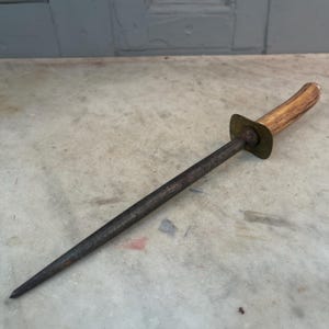 Puede incluir: Un afilador de cuchillos vintage de acero con mango de madera y detalles en lat&oacute;n. El afilador mide aproximadamente 30 cm de largo.