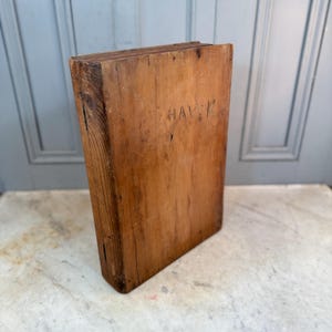 May include: A wooden box with the word "HAVN" inscribed on the front. The box is made of natural wood and has a rustic appearance.