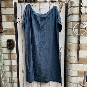 May include: A dark blue linen dress with a scoop neck and short sleeves hanging on a white wooden door.