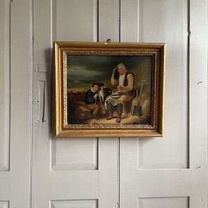 May include: An oil painting in a gold frame depicts two figures, one seated and one standing, with a dog in the scene. The figures are dressed in period clothing and the painting has a rustic background.