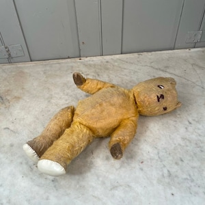 Puede incluir: Un oso de peluche vintage, amarillo, de peluche, con brazos y piernas de madera marr&oacute;n. El oso tiene una nariz cosida y ojos bordados.