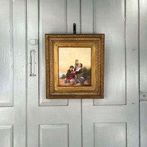 May include: A framed oil painting depicting three children in a coastal setting. The children are dressed in simple clothing and are interacting with each other. The painting has a warm, nostalgic feel.