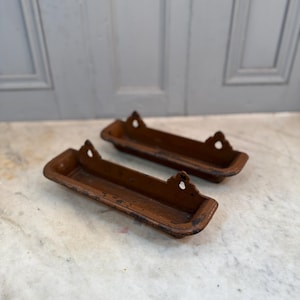 May include: Two brown metal wall mounted shelves with decorative edges. The shelves are empty.