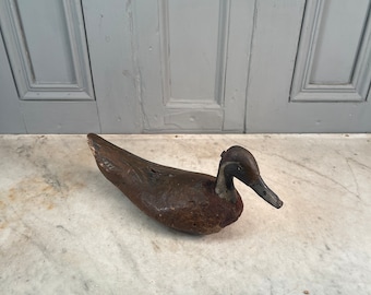 May include: A vintage wooden duck decoy with a dark brown finish. The decoy has a long, slender body and a detailed head with a black beak.