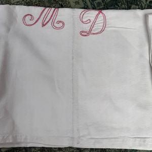 Peut inclure: Tissu de lin blanc avec des lettres brodées roses "M" et "D" dans les coins supérieur gauche et droit.