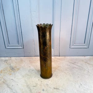 Puede incluir: Una taza de cerámica blanca con un asa negra y el texto "But First, Coffee" en un estilo manuscrito. La taza está sobre una superficie blanca. La taza mide 10 cm de alto.