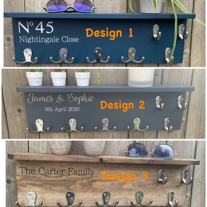 Op de afbeelding: Drie verschillende ontwerpen van houten sleutelrekken met haken. De eerste is donkerblauw geverfd met de tekst "N&deg;45 Nightingale Close" en "Design 1". De tweede is donkergrijs geverfd met de tekst "James & Sophie 9th April 2020" en "Design 2". De derde is van natuurlijke houtkleur met de tekst "The Carter Family" en "Design 3".
