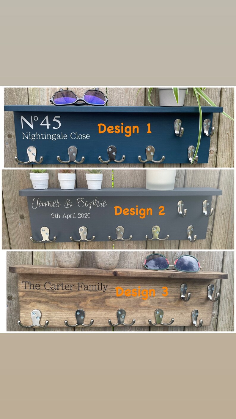 Op de afbeelding: Drie verschillende ontwerpen van houten sleutelrekken met haken. De eerste is donkerblauw geverfd met de tekst "N&deg;45 Nightingale Close" en "Design 1". De tweede is donkergrijs geverfd met de tekst "James & Sophie 9th April 2020" en "Design 2". De derde is van natuurlijke houtkleur met de tekst "The Carter Family" en "Design 3".