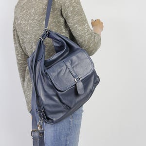 Könnte beinhalten: Marineblaue Schultertasche aus Leder mit Klappenverschluss und verstellbarem Riemen. Die Tasche hat eine strukturierte Oberfläche und silberfarbene Hardware. Die Tasche wird über der Schulter getragen und hat einen lässigen Stil.