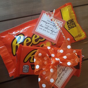 May include: A King Size Reese's Peanut Butter Cup wrapped in orange and yellow foil with a white and orange polka dot ribbon and a small tag that says "Have we recently told you how thankful we are for you?"