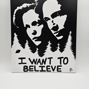 May include: Black and white canvas art featuring two faces and the text "I WANT TO BELIEVE". The artwork has a minimalist style with a forest silhouette at the bottom. The canvas measures 16x20 inches.