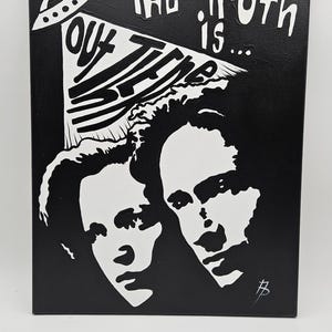 May include: Black and white canvas art featuring two faces and the text "The Truth is... Out There" with a UFO graphic. The artwork is rectangular and measures 16 x 20 inches.