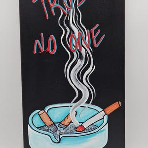 May include: Acrylic painting on canvas with a black background. The words "TRUST NO ONE" are written in red and teal. A blue ashtray with two cigarettes and smoke rising from it is in the foreground.