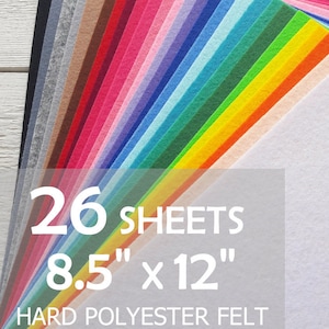 May include: A collection of 26 sheets of hard polyester felt arranged in a fan shape, featuring a wide spectrum of colours including white, yellow, green, blue, purple, pink, red, brown, grey, and black. Text reads 26 SHEETS 8.5" x 12".