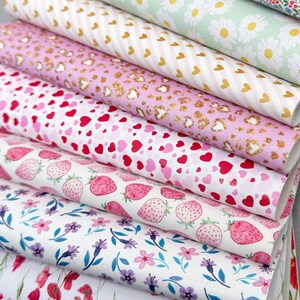 May include: A stack of patterned faux leather sheets. Designs include daisies, hearts, strawberries, and floral patterns in various colors like pink, white, and green. The sheets are suitable for crafting and DIY projects.