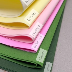 May include: A stack of six flexible foam sheets in various colors, each labeled with a white rectangular sticker. The colors from top to bottom are ivory, lemon, flamingo, barbie pink, green, and dark green, arranged in a layered, fanned-out display.