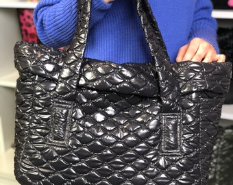 May include: A black quilted tote bag with a diamond pattern. The bag has two top handles and a zipper closure.