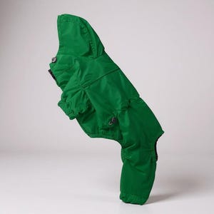 May include: A vibrant green dog jacket with a hood, designed for outdoor wear. The jacket features a button closure and a tailored fit, providing protection from the elements. The jacket is made of a durable, water-resistant material.