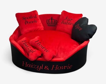 May include: A round pet bed with a black exterior and red interior. It features two red square pillows embroidered with "Spoiled Pooch" and "Fur Babies", two red bone-shaped pillows labeled "Haizyl" and "Howie", and a black heart pillow with "Love".