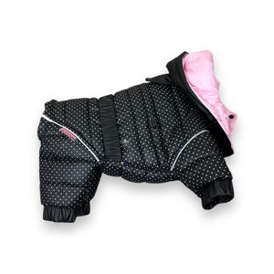 May include: Black and white polka dot dog coat with a pink hood. The coat has a zipper closure and a reflective strip on the back.
