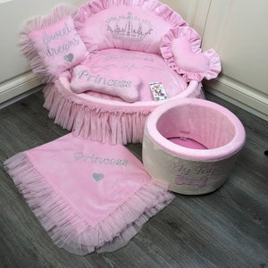 May include: Pink princess dog bed with a crown, a bone-shaped pillow, and a separate pink and white dog bed with the words "My Toys".
