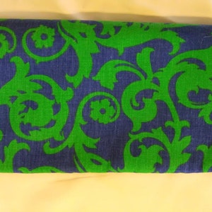 May include: A rectangular fabric item with a navy blue background and a vibrant green floral pattern. The design features stylized, swirling leaves and flower-like shapes, creating a bold, eye-catching aesthetic. The fabric appears to be tightly woven.