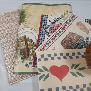 May include: Assortment of decorative wallpaper borders featuring a variety of patterns, including a checkered design, a floral design with strawberries, a basket, and a heart design. The borders are printed on a cream-colored background.