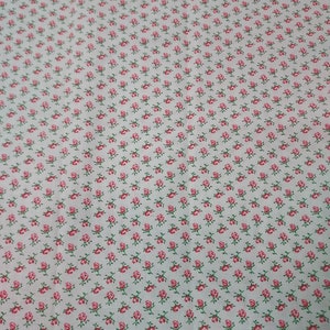 May include: White fabric with a repeating pattern of small pink roses with green stems.