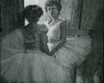 Op de afbeelding: Twee vrouwen op een zwart-witfoto, een draagt een witte jurk en de andere een witte tutu. De vrouw in de tutu staat met haar rug naar de camera, terwijl de vrouw in de witte jurk naar de camera kijkt. De foto is gemaakt in een kamer met een houten vloer en een deuropening op de achtergrond.