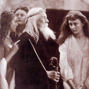 May include: A black and white photograph of three people. A man with a long white beard and a crown is standing in the center. A woman with a crown is standing on the left, and a woman with long hair is standing on the right. The man is holding a staff.