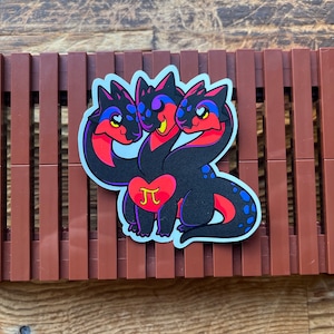 May include: A sticker of a three-headed black, red, and blue dragon holding a heart with a pi symbol inside. The dragon has a white outline.