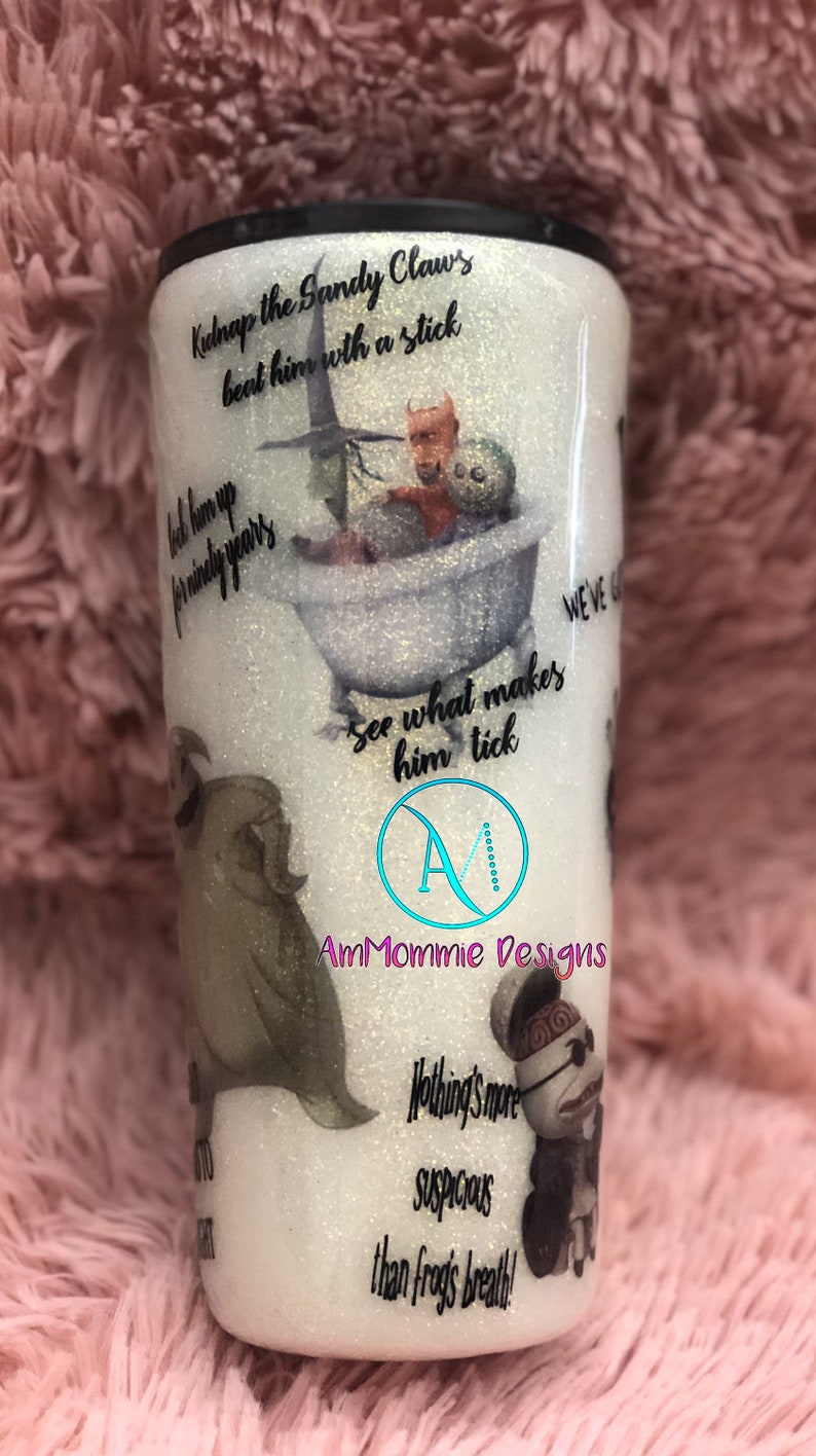 Puede incluir: Un vaso blanco con purpurina con una imagen en blanco y negro de personajes de la pel&iacute;cula "Pesadilla antes de Navidad". El vaso tiene texto que dice "Kidnap the Sandy Claws beat him with a stick", "Look him up for ninety years", "See what makes him tick", "Nothing's more suspicious than frogs breath!" y "AmMommie Designs".