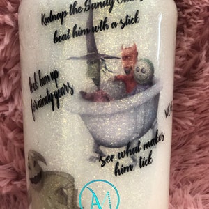 Puede incluir: Un vaso blanco con purpurina con una imagen en blanco y negro de Jack Skellington de la pel&iacute;cula Pesadilla antes de Navidad. El vaso tiene el texto "Kidnap the Sandy Claws beat him with a stick lock him up for ninety years see what makes him tick" impreso en &eacute;l. El vaso tambi&eacute;n tiene el texto "AmMommie Designs" impreso en &eacute;l.