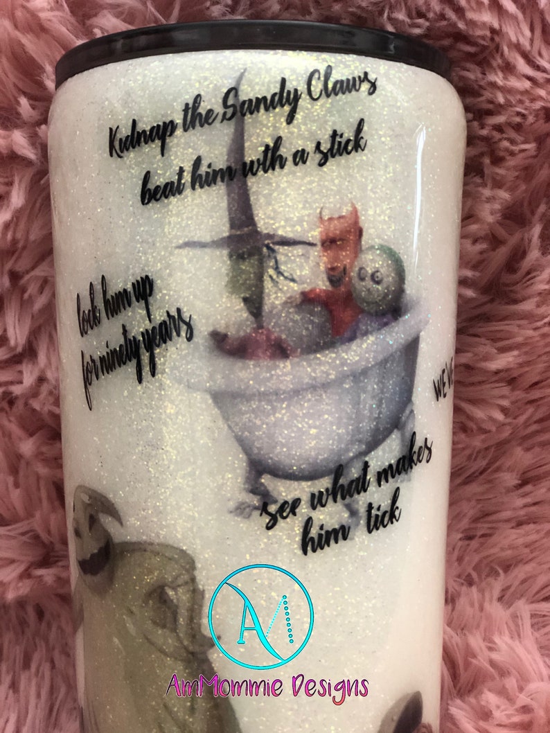 Puede incluir: Un vaso blanco con purpurina con una imagen en blanco y negro de Jack Skellington de la pel&iacute;cula Pesadilla antes de Navidad. El vaso tiene el texto "Kidnap the Sandy Claws beat him with a stick lock him up for ninety years see what makes him tick" impreso en &eacute;l. El vaso tambi&eacute;n tiene el texto "AmMommie Designs" impreso en &eacute;l.