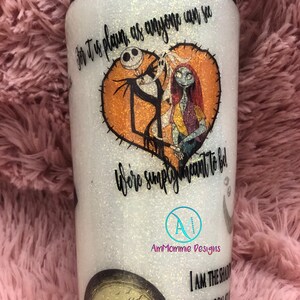 Puede incluir: Un vaso blanco con purpurina y una tapa negra. El vaso presenta un gr&aacute;fico de Jack Skellington y Sally de la pel&iacute;cula Pesadilla antes de Navidad. El texto "For it is plain as anyone can see, we're simply meant to be" est&aacute; impreso en el vaso. El vaso tambi&eacute;n presenta un gr&aacute;fico de luna con una silueta de Jack Skellington. El texto "I am the shadow on the moon at night, filling your dreams with fright" est&aacute; impreso en el vaso. El vaso est&aacute; decorado con un logotipo en blanco y negro que dice "AmMommie Designs".