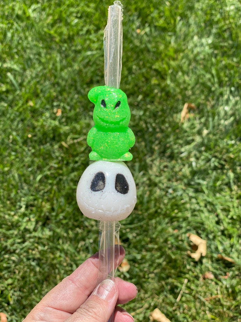 Puede incluir: Una pajita tem&aacute;tica de personajes verde y blanca con un personaje verde con una sonrisa de dientes de punta a punta encima de un personaje blanco con ojos negros. La pajita es de pl&aacute;stico transparente.