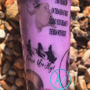 May include: Purple glitter tumbler with a silhouette of the Sanderson sisters from Hocus Pocus flying on broomsticks. The text "Come We Fly!" is written in black cursive. The tumbler also features a silhouette of the ghost from the movie "The Nightmare Before Christmas" and the text "I am the shadow on the moon at night filling your dreams to the brim with fright".